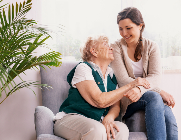 Senior,Lady,Sitting,In,Armchair,At,Nursing,Home,,Supporting,Nurse